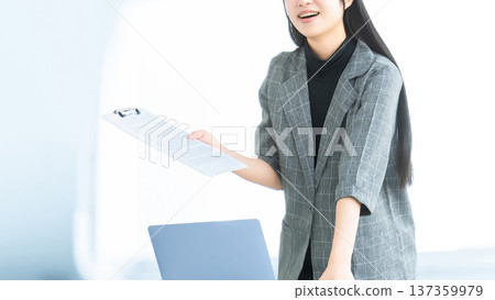 一位年輕女子/女商人手持文件,正在發表聲明/提出建議。 一位年輕女子/女商人手持文件,正在發表聲明/提出建議。 137359979