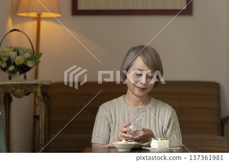 Senior woman having a drink in the living room Senior woman having a drink in the living room 137361981