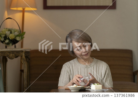 Senior woman having a drink in the living room Senior woman having a drink in the living room 137361986