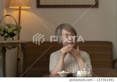 Senior woman having a drink in the living room Senior woman having a drink in the living room 137361991