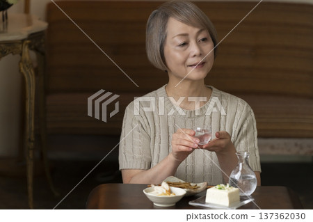 Senior woman having a drink in the living room 137362030