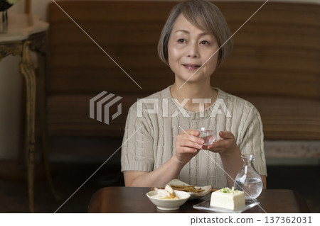 一位老婦人在客廳喝飲料 一位老婦人在客廳喝飲料 137362031