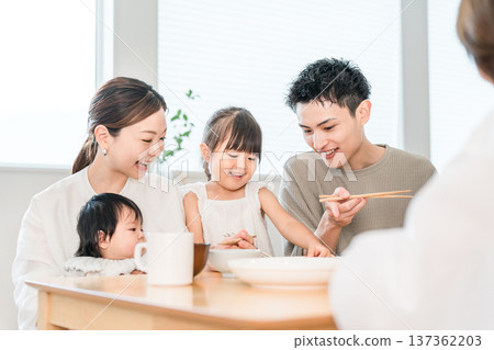 Girl and family practicing using chopsticks while playing house at the dinner table, Family Girl and family practicing using chopsticks while playing house at the dinner table, Family 137362203