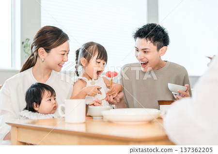 Girl and family practicing using chopsticks while playing house at the dinner table, Family Girl and family practicing using chopsticks while playing house at the dinner table, Family 137362205