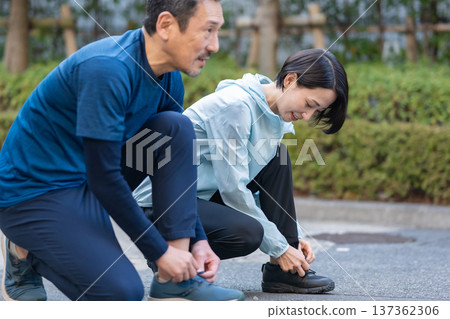 Men and women tying shoelaces Men and women tying shoelaces 137362306
