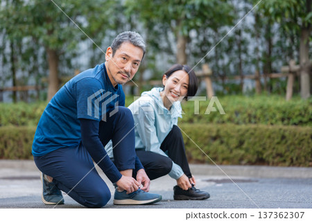 Men and women tying shoelaces Men and women tying shoelaces 137362307