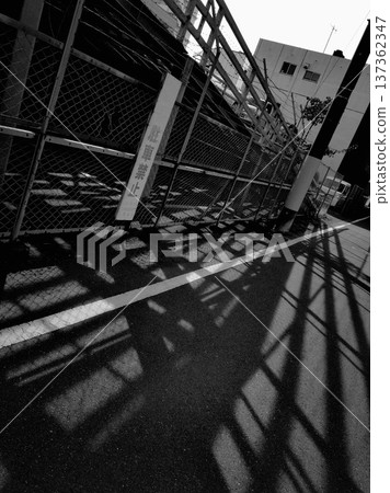 Shadow of a fence falling on the road High contrast monochrome photo 137362347