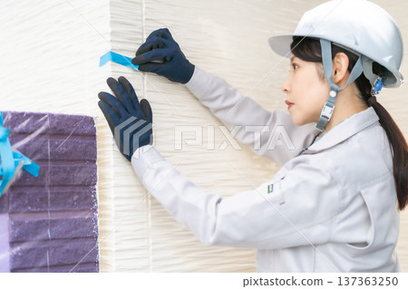 A female engineer marking and inspecting the exterior wall 137363250