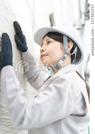 A female construction engineer inspecting and maintaining a house A female construction engineer inspecting and maintaining a house 137363257