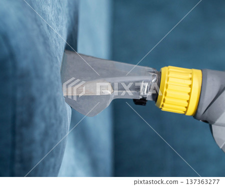 Cleaning a fabric sofa using a steam cleaner in a living room Cleaning a fabric sofa using a steam cleaner in a living room 137363277