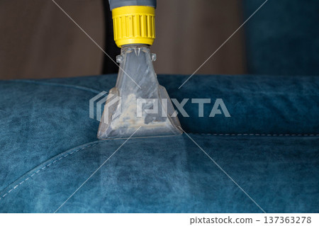 Deep cleaning of a blue upholstered sofa using a cleaning tool for dirt removal 137363278