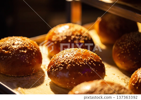 Warm golden brown brioche style buns with sesame seeds fresh from oven display. Delicious baked goods ready for consumption or preparation. Warm golden brown brioche style buns with sesame seeds fresh from oven display. Delicious baked goods ready for consumption or preparation. 137363392