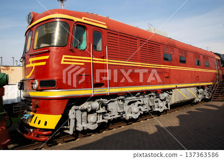 Vintage red train locomotive on display at railway museum under clear blue sky Vintage red train locomotive on display at railway museum under clear blue sky 137363586