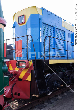 Colorful blue and yellow locomotive on railway tracks in an industrial setting during daytime Colorful blue and yellow locomotive on railway tracks in an industrial setting during daytime 137363587