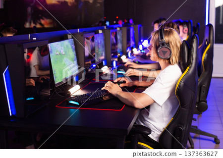 Team of gamers playing video game on PC at computer club, cyber sport tournament. E-sport championship. 5 players in headset communicate with each other over mic. Multiplayer online competition Team of gamers playing video game on PC at computer club, cyber sport tournament. E-sport championship. 5 players in headset communicate with each other over mic. Multiplayer online competition 137363627