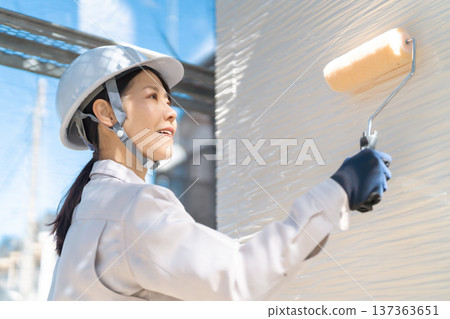 Female painting technician holding a roller at a home renovation site Female painting technician holding a roller at a home renovation site 137363651