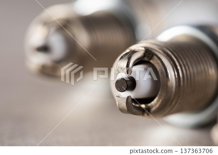 Detailed macro photograph of metallic automobile spark plugs, showing electrode tip, ground strap, and ceramic insulator, essential parts of combustion engine ignition 137363706