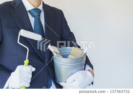 商人手提裝有油漆滾筒和刷子的水桶 | 裝修、油漆承包商、DIY 圖片 商人手提裝有油漆滾筒和刷子的水桶 | 裝修、油漆承包商、DIY 圖片 137363732