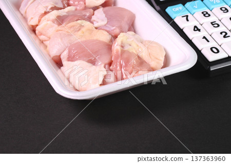 A tray of chopped chicken thighs and a calculator A tray of chopped chicken thighs and a calculator 137363960