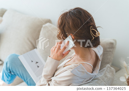 A stylish woman sitting on a sofa and talking on a smartphone 137364025