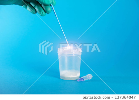 The hand of a laboratory doctor collects sperm biomaterial on a blue background for IVF donation. Copy space for text 137364047