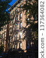 Historic New York residential building facade with fire escapes and sunlight through trees 137364082