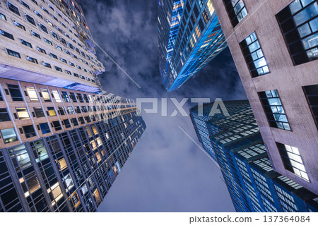 Upward night view of New York City skyscrapers forming dramatic urban canyon 137364084
