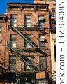 Classic New York brick apartment facade with metal fire escape stairs 137364085