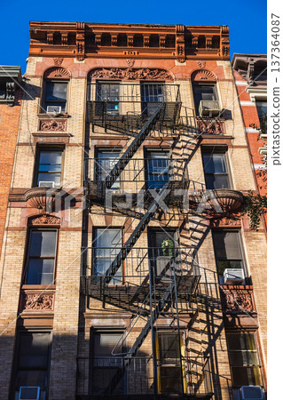 Historic New York apartment building facade with fire escape stairs Historic New York apartment building facade with fire escape stairs 137364087