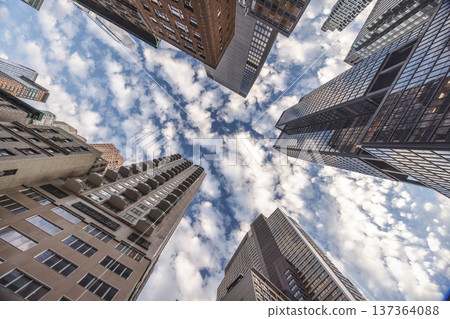 Dramatic upward view of New York City skyscrapers forming urban canyon with cloudy sky 137364088