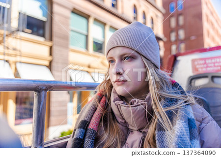 Young woman wearing winter hat and scarf sitting on open top bus in New York City 137364090
