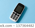 White push-button mobile phone on a blue background 137364482