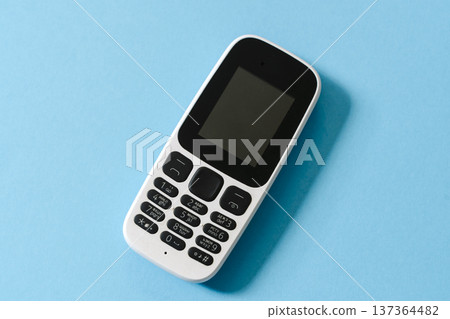 White push-button mobile phone on a blue background White push-button mobile phone on a blue background 137364482