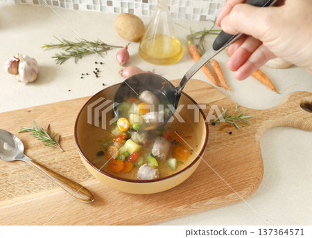 Traditional Italian minestrone soup with vegetables, sausage, served in clay bowl on wooden board. Food and healthy lifestyle. Mediterranean cuisine. Traditional Italian minestrone soup with vegetables, sausage, served in clay bowl on wooden board. Food and healthy lifestyle. Mediterranean cuisine. 137364571