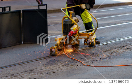 Close up of construction worker grinding tram rails with heavy machine. Urban maintenance, infrastructure repair, roadworks and industry concept. 137366073