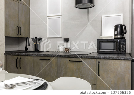 Modern Kitchen Workspace with Stone Textured Cabinets and Black Sink 137366336