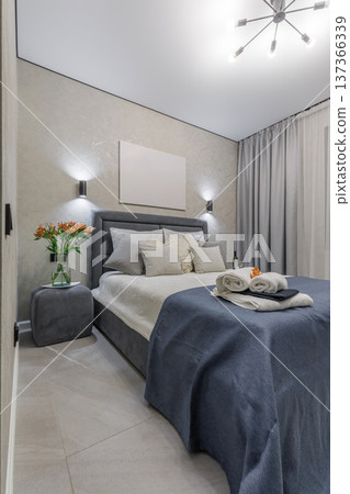 Modern Bedroom with Grey Bed, Blue Textiles and Orange Flowers 137366339
