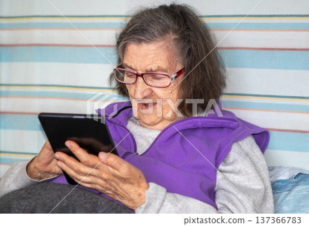 Elderly woman using tablet at home, relaxed senior reading and enjoying digital technology 137366783