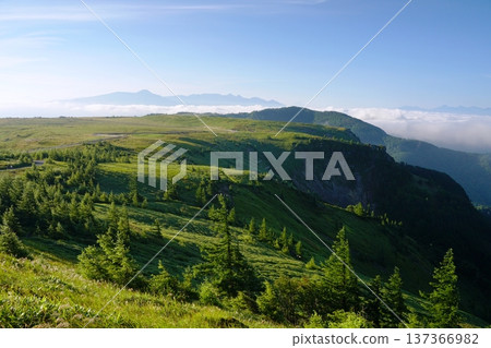 The Utsukushigahara Plateau in summer shines green against the backdrop of blue skies and the Yatsugatake mountain range. The Utsukushigahara Plateau in summer shines green against the backdrop of blue skies and the Yatsugatake mountain range. 137366982