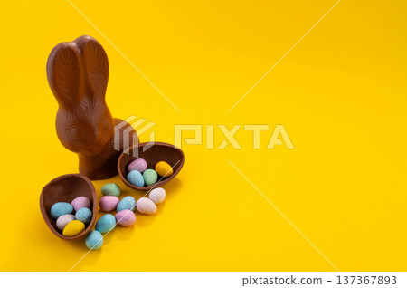Chocolate Easter eggs and chocolate bunny with copy space on a yellow background. 137367893