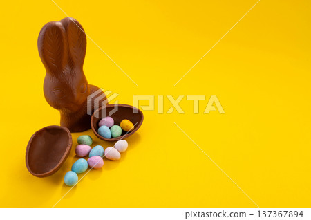 Chocolate Easter eggs and chocolate bunny with copy space on a yellow background. 137367894