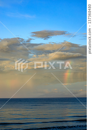 Dramatic skyscape of rain and rainbow over the sea 137368480