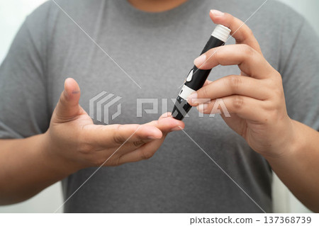 Asian woman self testing to check blood sugar level diabetes by digital lancet on finger at home. Asian woman self testing to check blood sugar level diabetes by digital lancet on finger at home. 137368739