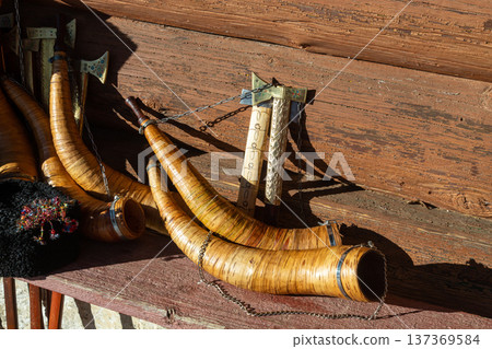 Traditional wooden horns and tools displayed on a rustic wooden shelf showcasing craftsmanship in an outdoor setting Traditional wooden horns and tools displayed on a rustic wooden shelf showcasing craftsmanship in an outdoor setting 137369584