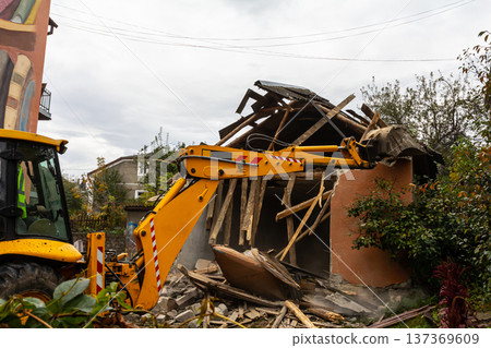 Heavy machinery demolishes a damaged building in an urban environment on a cloudy day 137369609