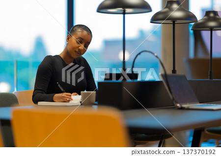 Woman writing notes in modern office 137370192