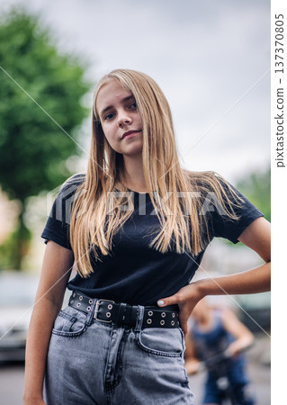 Blonde teen girl posing confidently with street style, expressing individuality outdoors Blonde teen girl posing confidently with street style, expressing individuality outdoors 137370805