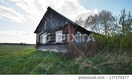 Old wooden abandoned house in slavic village surrounded by green grass and trees Old wooden abandoned house in slavic village surrounded by green grass and trees 137370877