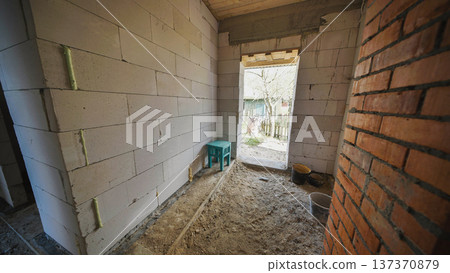 Interior room of a house under construction with building materials and brick walls 137370879