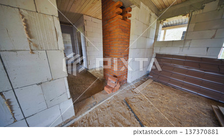 Interior house construction with an unfinished brick chimney and white block walls Interior house construction with an unfinished brick chimney and white block walls 137370881